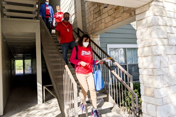 Four AISD Operation Reconnect volunteers walk down apartment complex stairs